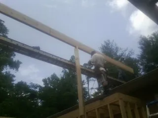Carpenter setting a ridge beam over a new addition frame — Ice Dam Removal by Roofing Brothers in Parrish