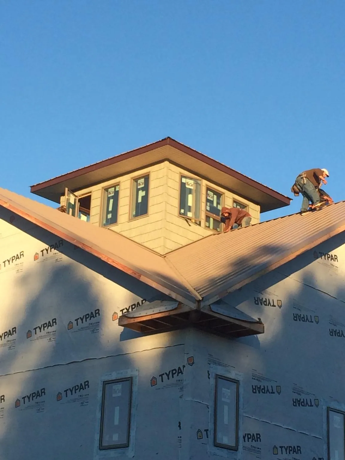 Roofers working around a rooftop cupola on a new metal roof at sunset — Roof Waterproofing in Parrish by Roofing Brothers